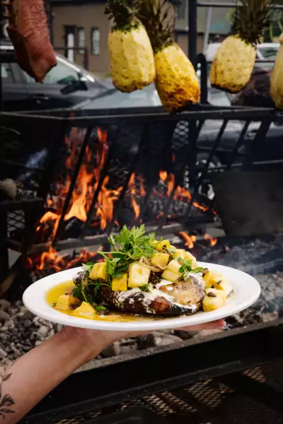 Fat Rabbit: A dish with roasted pineapple is held in front of a fire at Fat Rabbit