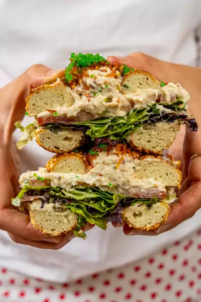 Farm-to-table dining in Qu&eacute;bec: A hand holds a stacked bagel open at Chez Greenberg