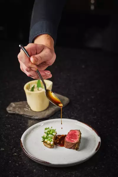 Farm-to-table dining in Qu&eacute;bec: A hand pours sauce at Tani&egrave;re&sup3; in Quebec City