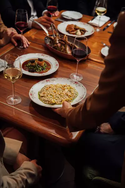 REIGN Toronto | A hand delivers a plate of risotta to a table spread with food and wine at REIGN