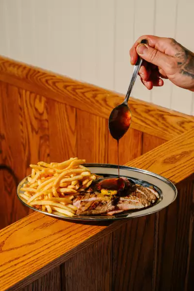 Best Ontario restaurants | A hand pours sauce on the Secreto Frites at Les Incompetents in St. Catherines