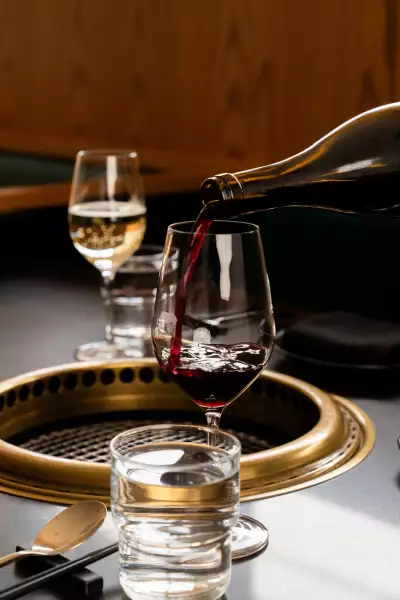 Takja BBQ | A hand pours red wine at Takja BBQ