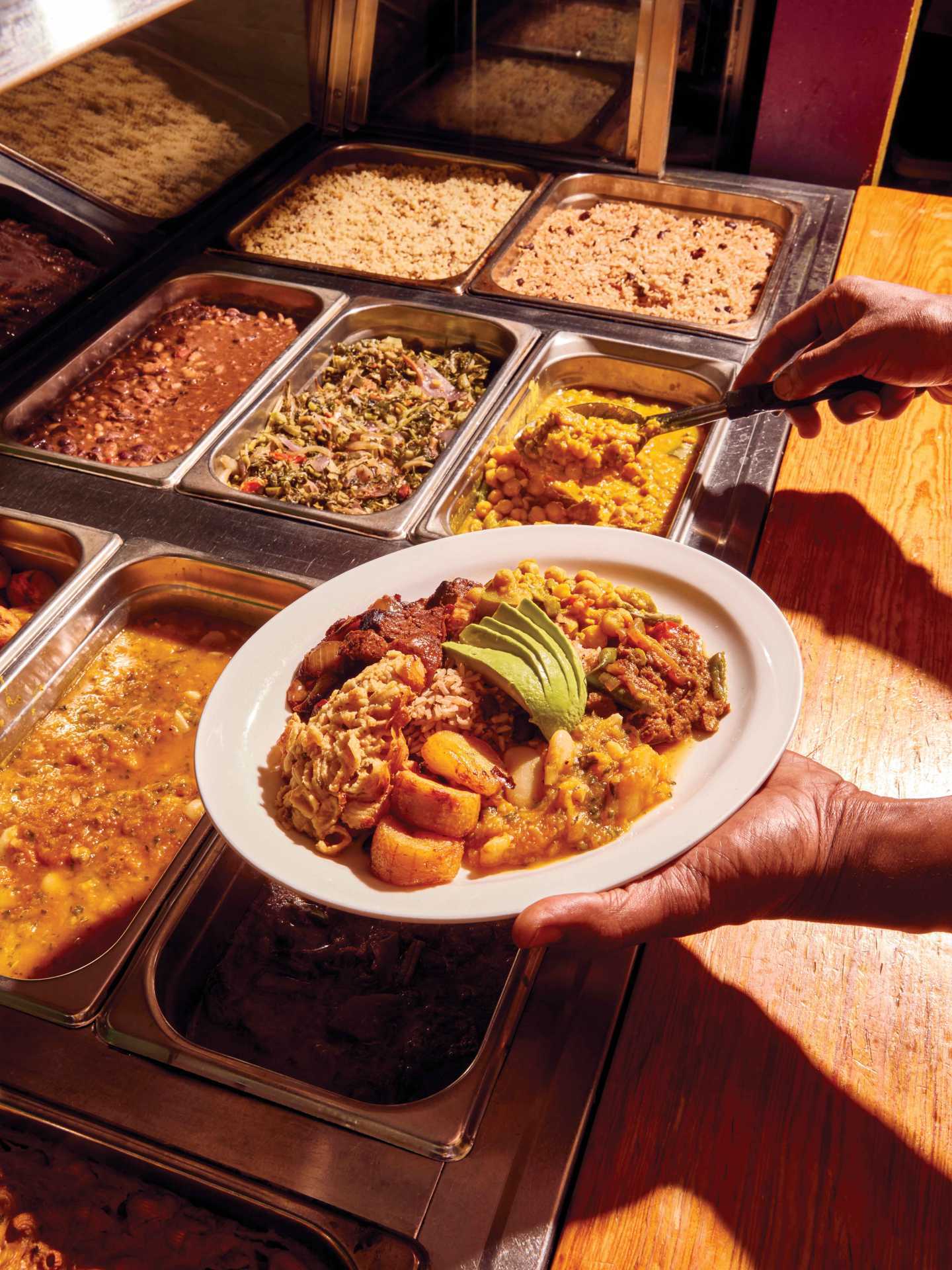 Vegan food in Toronto | Chef Pong scooping food onto a plate at V's Caribbean Restaurant Vegan food in Toronto | Chef Pong scooping food onto a plate at V's Caribbean Restaurant