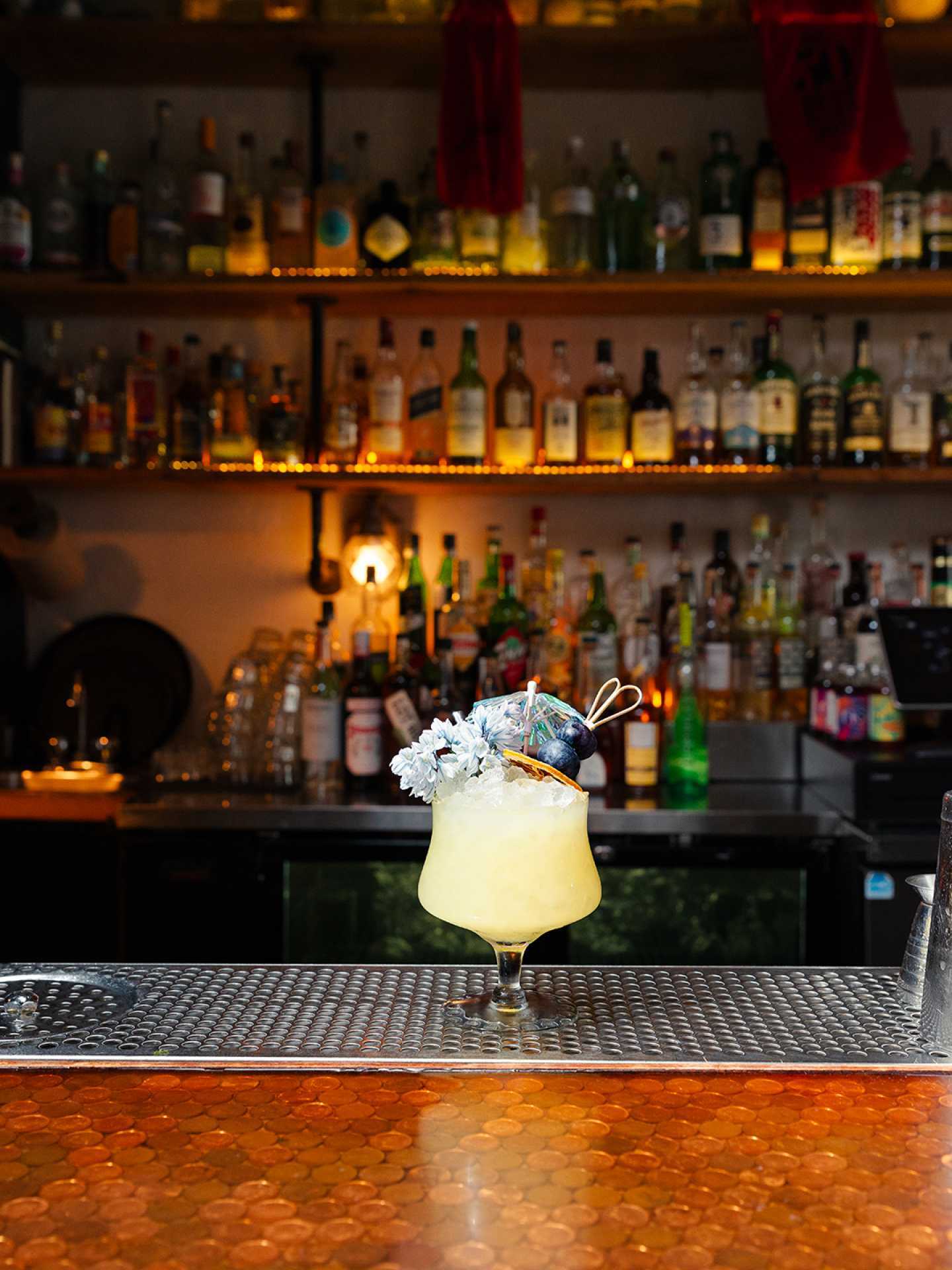The best bars in Toronto | A yellow, tropical cocktail garnished with flowers and blueberries at Civil Liberties