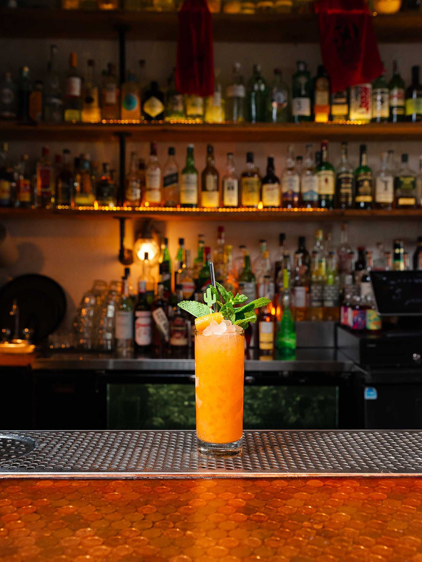 The best bars in Toronto | A tall orange cocktail garnished with herbs at Civil Liberties in Toronto