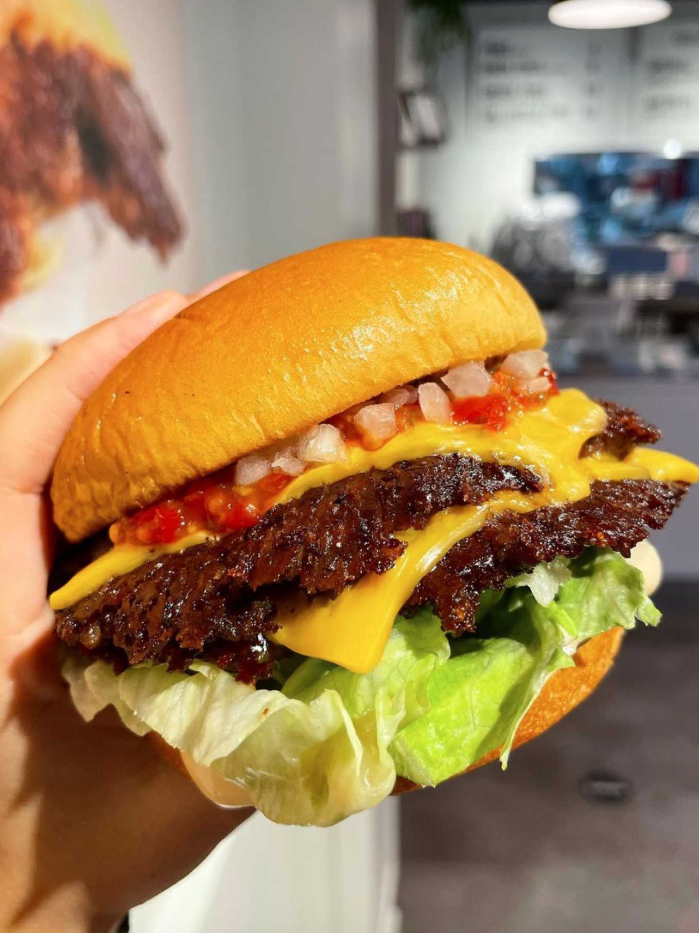 The best burgers in Toronto | Someone holding a smash burger at Burger Drops