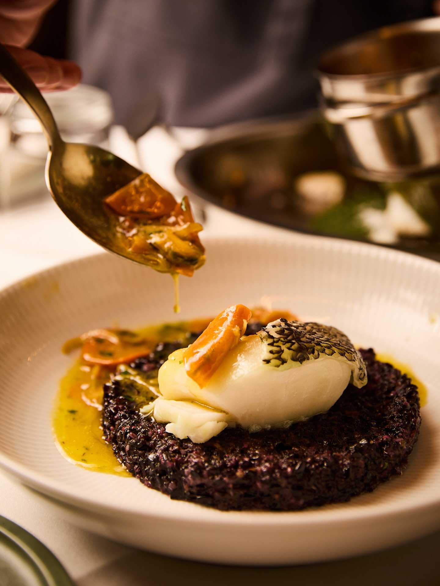 New restaurants | A hand spoons sauce over an octopus dish at Riley's Toronto