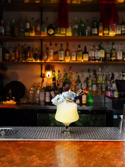 The best bars in Toronto | A yellow, tropical cocktail garnished with flowers and blueberries at Civil Liberties