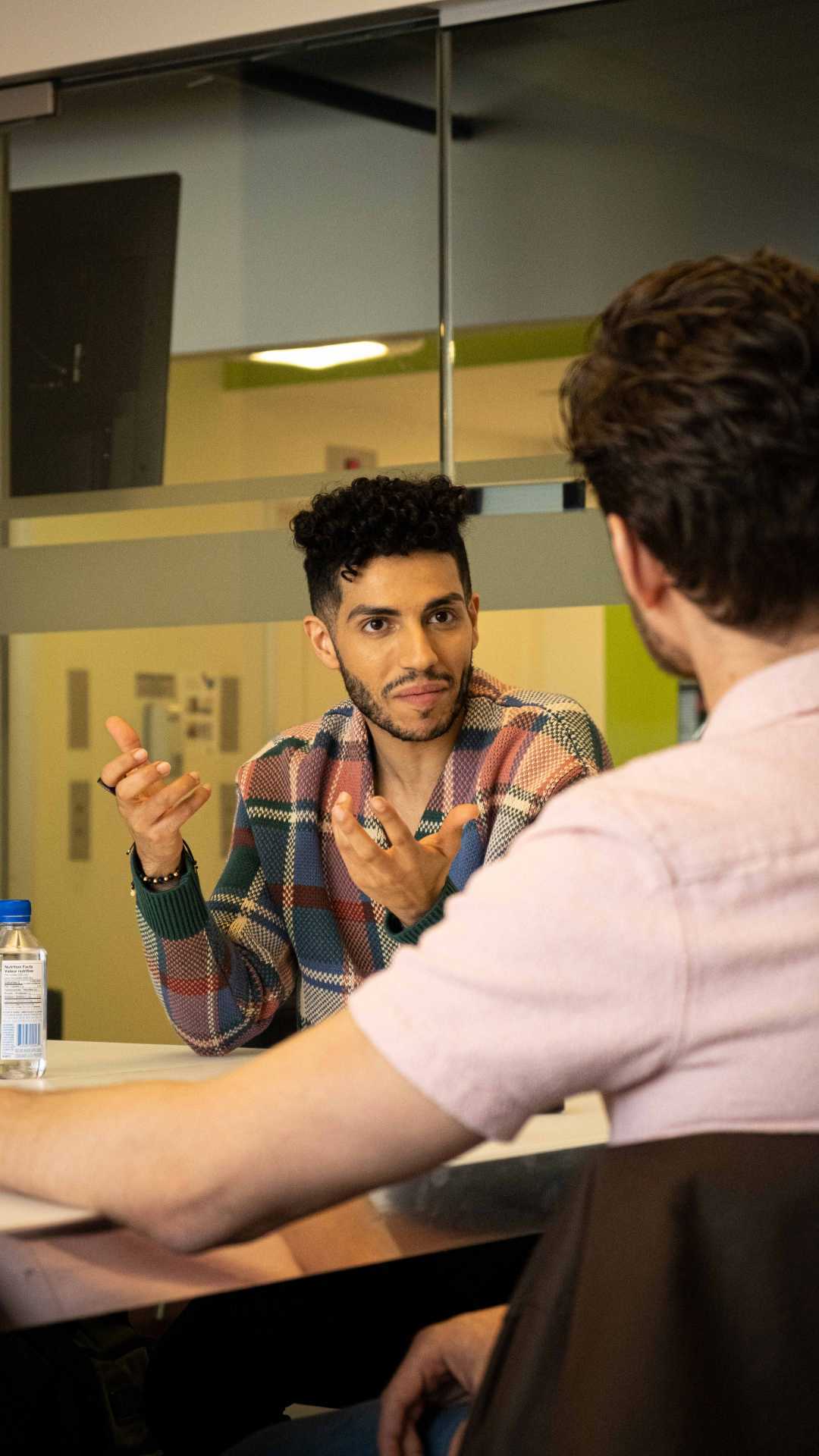 Mena Massoud | Aladdin actor Mena Massoud having a conversation at a table Mena Massoud | Aladdin actor Mena Massoud having a conversation at a table
