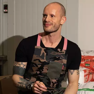 Ruben Rapetti sitting by sacks of potatoes smiling with pasta in his hand