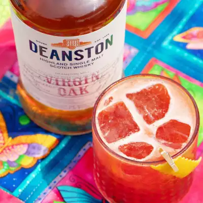 A red cocktail and a bottle of Deanston Virgin Oak