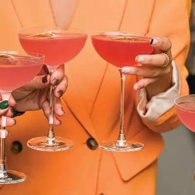 Three people holding red cocktails