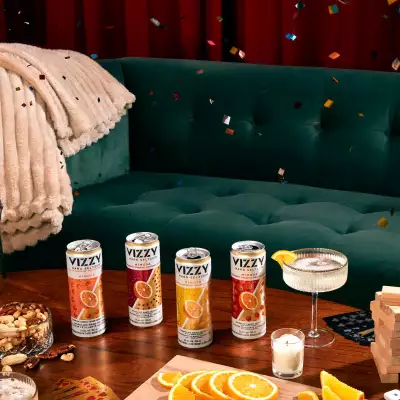 Cans of Vizzy Mimosa Hard Seltzer on a coffee table with confetti