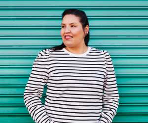 Carrie Rau, chef, sommelier and co-founder of Vinequity, stands in front of a green background
