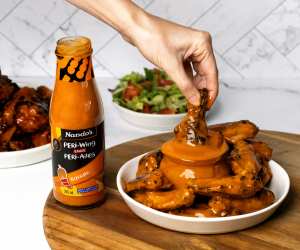 Dunking a wing into Nando's Buffalo PERi Wing Sauce