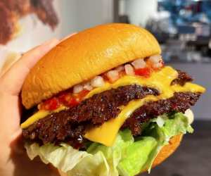 The best burgers in Toronto | Someone holding a smash burger at Burger Drops