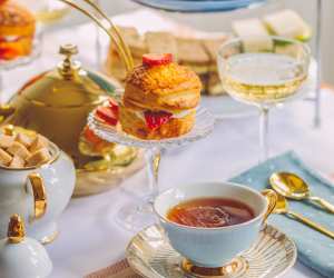 UK Guide to Food and Wine | A table is set for afternoon tea with scones, a cup and saucer and a glass of sparkling wine