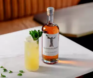 A bottle of Glendalough Double Barrel Irish Whiskey with a yellow cocktail