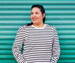 Carrie Rau, chef, sommelier and co-founder of Vinequity, stands in front of a green background