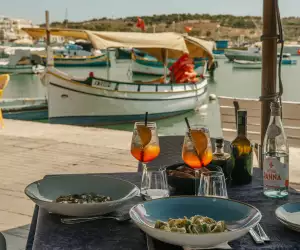 Malta's Michelin moment | A table with Aperol spritzes, food and a view of a boat on the water in Malta
