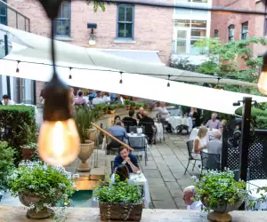 George Restaurant | A view between the twinkling lights of diner on the courtyard patio at George Restaurant